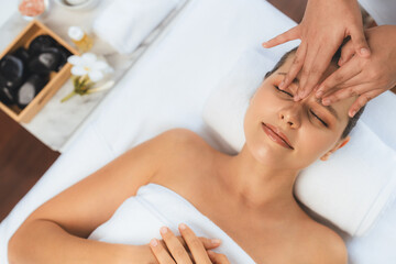 Fototapeta premium Panorama top view of woman enjoying relaxing anti-stress head massage and pampering facial beauty skin recreation leisure in dayspa modern light ambient at luxury resort or hotel spa salon. Quiescent