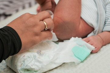 Closeup Mother changing her baby's diaper on bed, Woman taking care of baby.