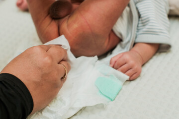Closeup Mother changing her baby's diaper on bed, Woman taking care of baby.