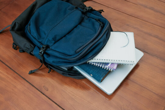 Blue backpack with books, notepad and laptop for student or working on the wooden table, concept back to school or working.