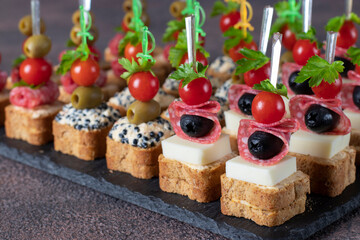 Assortment of canapes with cherry tomatoes, sausage, cheese, olives and seaweed caviar