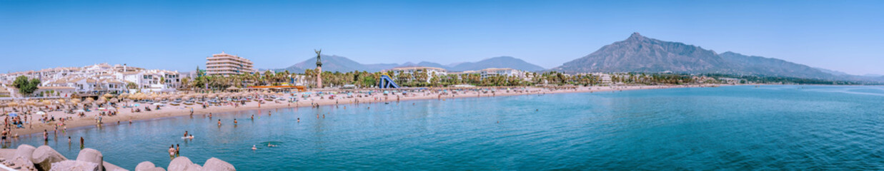 Tourists relaxing on the beach of Estepona, Spain, with concha mountain looming. PUERTO BANUS, MARBELLA 