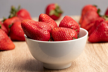 vista cenital de frutillas en un plato blanco rodeado de fresas
