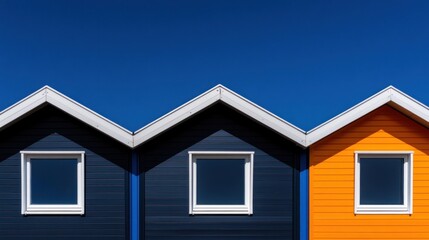 Three houses with distinct colors stand out against a clear blue sky, showcasing modern architectural design and vibrant hues in a cheerful neighborhood