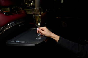 An Elegant Hand Holding a Glass of Exquisite White Wine While in a Luxurious Car Setting