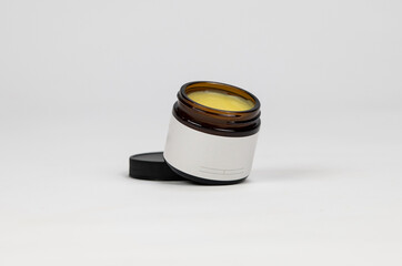 Blank label on amber salve cosmetic jar white background