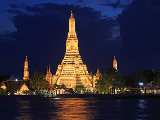 Fototapeta premium Wat Arun Temple illuminated at night with nice reflections in the river in Bangkok, Thailand