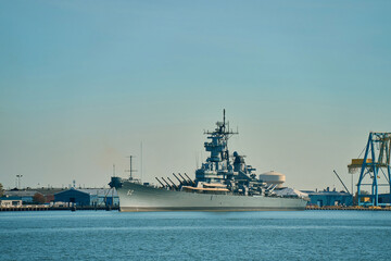 A large warship is moored at the pier