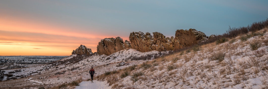winter sunrise over a trail at Colorado foothills with a distant runner - Devils Backbone rock formation near Loveland
