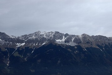 Majestic Mountain Range Covered in Early Snow with Misty Clouds in Moody Skies. Tirol, Austria.