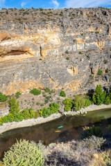 Hoces del Rio Duraton Nature Reserve (Parque Natural de las Hoces del R&iacute;o Durat&oacute;n) with limestone vertical cliffs, blue water and colorful kayaks floating.