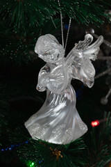 glass angel decorates the Christmas tree. Delicate Angel Ornament on Christmas Tree with Twinkling Lights and Sparkling Tinsel