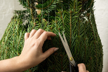 A child carefully cutting the net of a real Nordmann fir Christmas tree. The photo reflects the warmth of family and holiday preparation.
