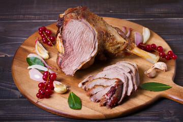 Roasted leg of lamb on serving board with potatoes and broccoli