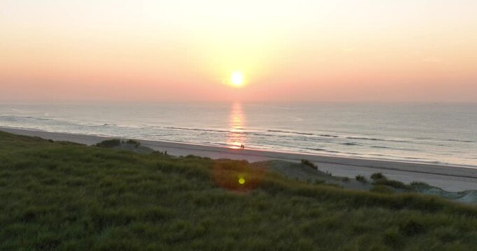 aerial view on couple having romantic beach walk at golden hour sunset.
