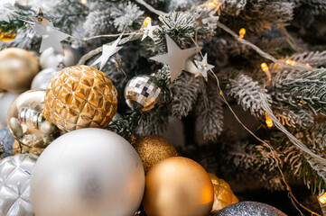 Close-up of a beautifully decorated Christmas tree with frosted branches, golden and silver ornaments, and festive lights. Perfect for holiday themes, winter, and celebration imagery