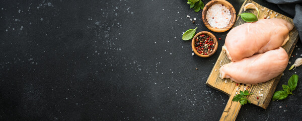 Chicken fillet, raw chicken meat breast with spices and herbs at dark background. Web banner format.