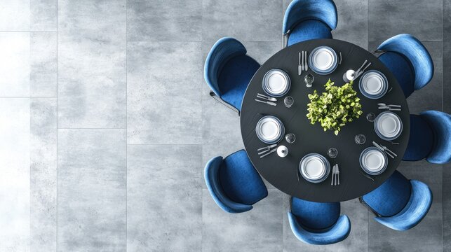 Elegant dining setup featuring a round table with blue chairs and a centerpiece of greenery.