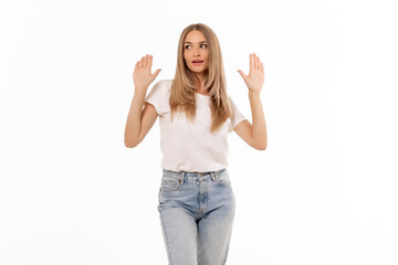 A young woman raises her hands in a gesture of surprise while wearing a casual outfit against a bright white background