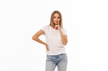 Fototapeta premium Young woman in casual clothing poses thoughtfully against a plain white background during a studio photoshoot