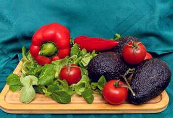 Ripe Avocado on a Wooden Board with Fresh Spinach, Red Tomatoes, and Red Peppers