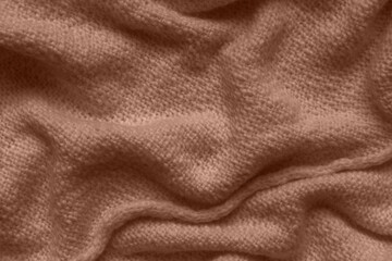 Texture of brown knitted woolen fabric with folds