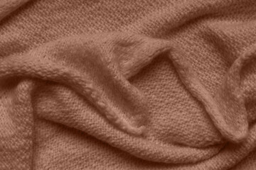 Texture of brown knitted woolen fabric with folds