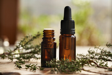 Two bottles of aromatherapy essential oil with thyme leaves