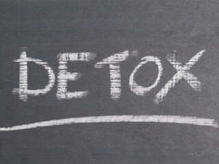 the word "detox" written with white chalk on blackboard 