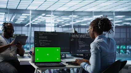 Diverse team of developers in server hub using green screen laptop, looking for misconfigurations....