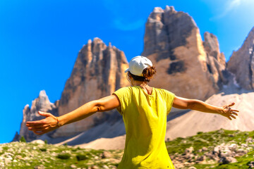 Tourist enjoying freedom in the dolomites with open arms in front of tre cime di lavaredo