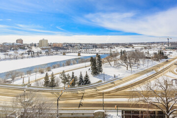 A snowy city street with a bridge in the background