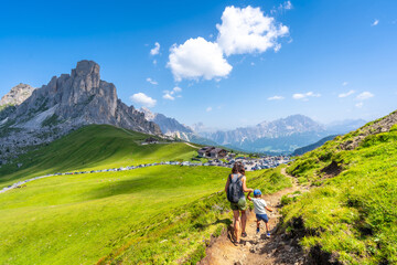 Obraz premium Tourists hiking in the dolomites, giau pass in summer, italy