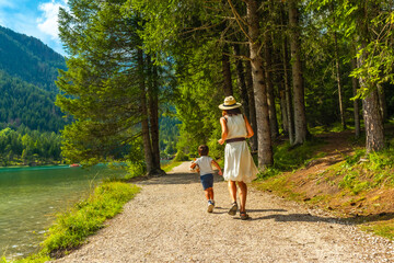 Mother and son walking along lake dobbiaco in the dolomites