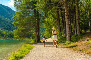 Tourists running along lake dobbiaco in the dolomites, italy