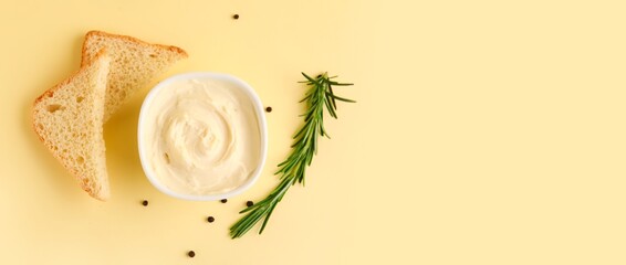 Bowl with tasty cream cheese and bread on yellow background with space for text
