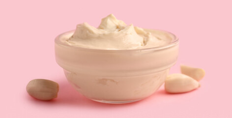 Bowl with tasty cream cheese on pink background