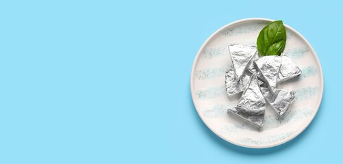 Plate with triangles of tasty processed cheese on blue background with space for text