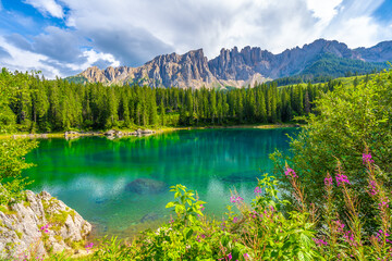 Latemar mountain group reflecting in the emerald water of lake carezza in summer