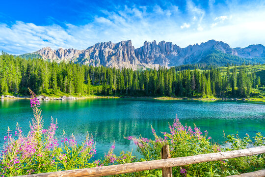 Karersee lake reflecting latemar mountain range in the dolomites on a clear summer day - Powered by Adobe
