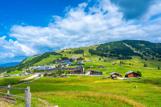 Green meadows and hotels on alpe di siusi with blue sky and white clouds during summer season