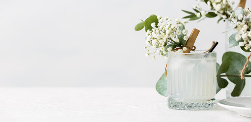 Glass with tasty cocktail and beautiful gypsophila flowers on light background