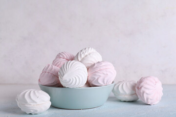 Bowl with delicious marshmallows on table against white background