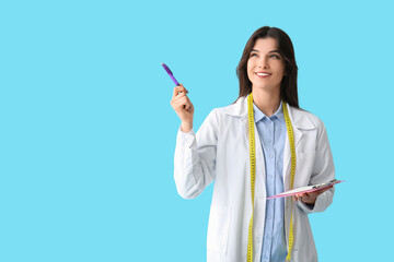 Female nutritionist with clipboard pointing at something on blue background
