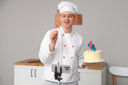 Male chef with sweet cake recording cooking video in kitchen