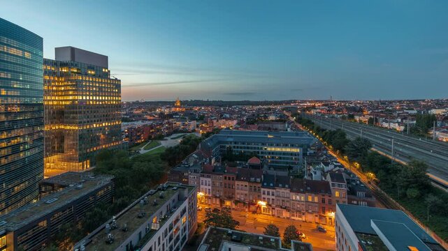 Aerial day to night transition timelapse of Brussels urban landscape blending office skyscrapers with residential areas. Green park lawns, historic rooftops and modern architecture in Belgium