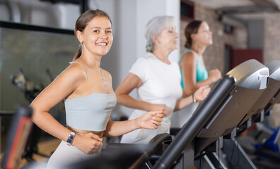 Fototapeta premium Girl in sportswear are running on treadmill. Physical activity, healthy lifestyle. Easy and simple weight loss, affordable workouts, active self-care in crossfit gym