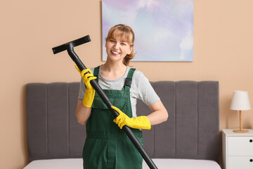 Female janitor with vacuum cleaner in bedroom