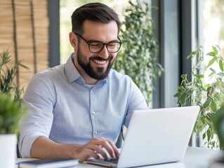 Fototapeta premium Man smiling while using a laptop in an office environment
