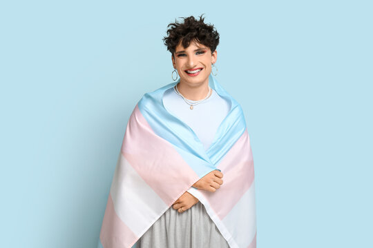 Young transgender woman with flag on blue background